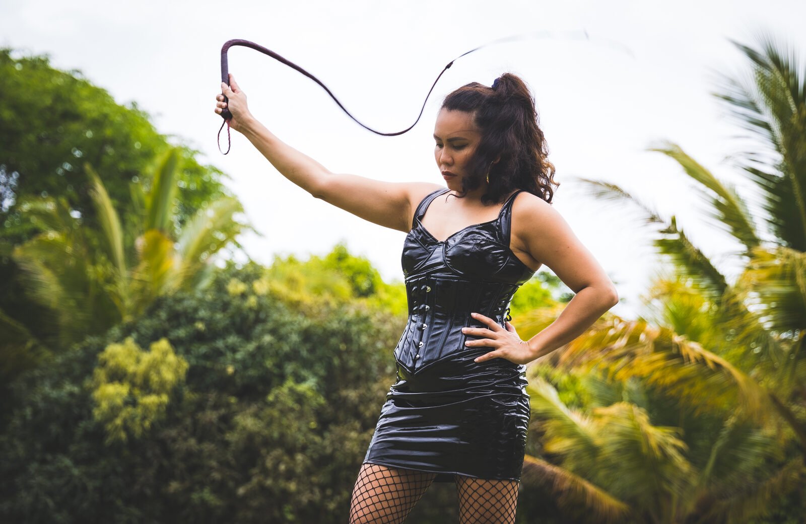 Domina Fire in Manila, holding a whip among palm trees